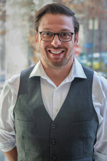 Micheal Lyons headshot in a white shirt and grey vest