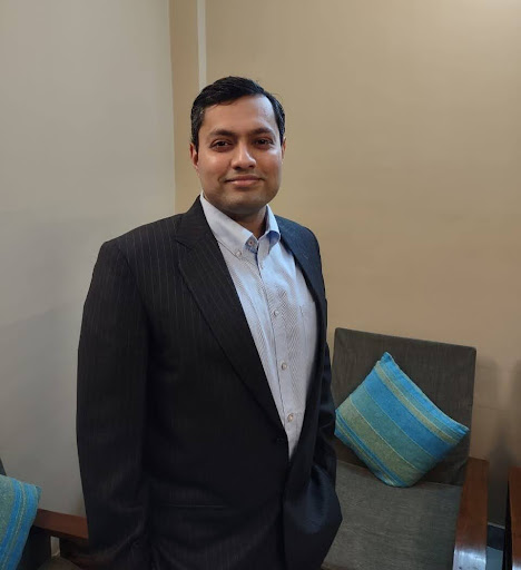 Zain Hoda in a black blazer and light blue button up shirt